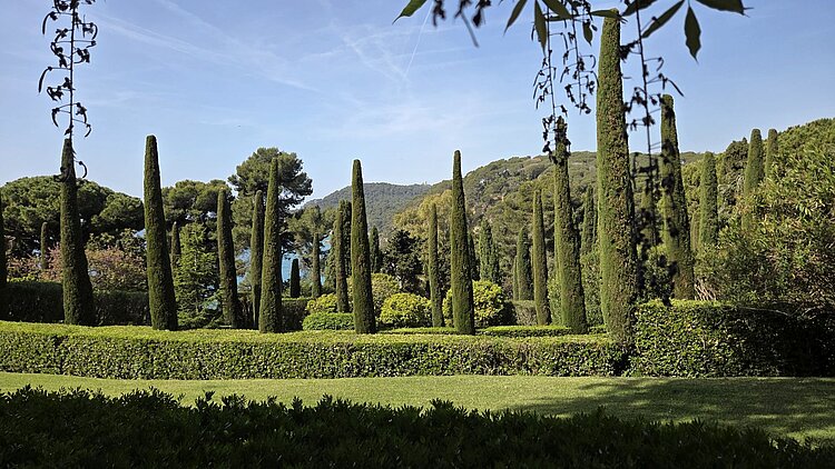 Blick durch die Jardins de Santa Clotilde in Lloret de Mar mit Zypressen und Mittelmeer im Hintergrund