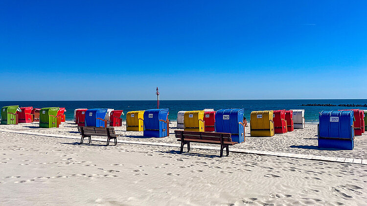 Bunte Strandkörbe am weißen Sandstrand der Helgoländer Düne unter blauem Himmel