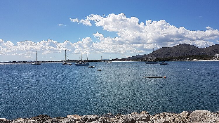 Bucht von Alcúdia auf Mallorca mit Segelbooten vor der Küste und Bergen im Hintergrund
